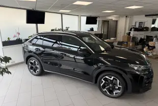 Volkswagen T-Roc R-Line noir intense en vue 3/4 avant droit, avec jantes alliage et vitres teintées, dans un showroom.