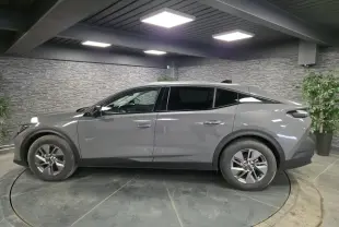 Peugeot 408 gris vue de profil côté gauche dans un showroom avec jantes alliage et vitres teintées.