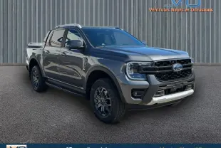 Ford Ranger gris en 3/4 avant droit, double cabine avec barres de toit et jantes alliage 17 pouces visibles.