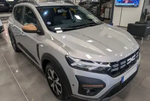 Vue 3/4 avant droit d'une Dacia Sandero Stepway 2023 gris Moonstone avec rétroviseurs bronze et détails noirs contrastants.