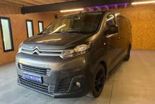 Vue 3/4 avant droit d'un Citroën Jumpy XL Spacetourer gris, avec calandre chromée et jantes noires, en intérieur.