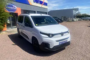 Vue 3/4 avant d'un Citroën Berlingo blanc 2025 avec portes coulissantes, stationné devant un bâtiment Distinxion.