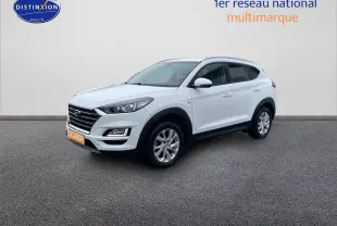 Hyundai Tucson blanc polaire vu en 3/4 avant droit, avec calandre noire et jantes alliage argentées.