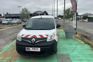 Vue avant d'un Renault Kangoo blanc 2020 avec bandes rouges diagonales sur le capot, garé sur un sol vert.