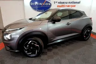 Nissan Juke Hybrid gris foncé vue de profil côté gauche, avec jantes noires et logo Distinxion en arrière-plan.