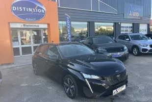 Peugeot 308 noire Perla Nera vue 3/4 avant gauche, garée devant un concessionnaire avec logo Distinxion visible.