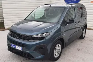Peugeot Rifter bleu Kiama en 3/4 avant droit, avec calandre noire et jantes argentées, stationné devant un mur blanc.