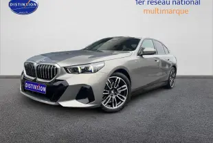 BMW Série 5 gris vue 3/4 avant droit, avec calandre imposante et jantes alliage distinctives.