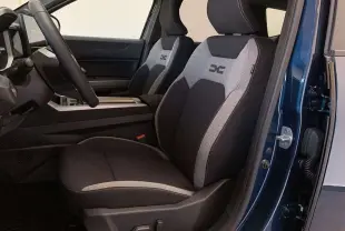 Vue intérieure côté conducteur du Dacia Bigster Hybrid 155 Journey Plus, sièges tissu noir et gris avec logo brodé.