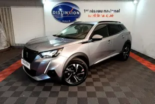 Peugeot 2008 gris clair en 3/4 avant droit, avec jantes noires et toit noir dans un showroom intérieur.