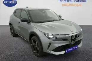 Vue 3/4 avant gauche d'une Alfa Romeo Junior hybride rechargeable grise avec phares LED et jantes noires distinctives.