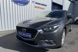 Vue 3/4 avant droite d'une Mazda3 gris métallisé 2017 avec calandre noire et phares LED visibles.
