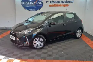 Toyota Yaris noire vue de profil côté gauche en intérieur, avec jantes argentées et phares allumés.