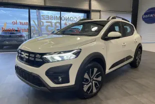 Vue 3/4 avant droite d'une Dacia Sandero Stepway 2025 blanc glacier avec jantes spécifiques et protections noires.