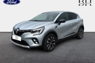 Renault Captur 1.6 E-Tech hybride gris Highland en 3/4 avant droit avec jantes alliage et toit noir.