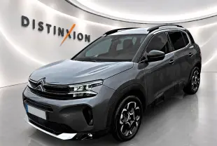 Citroën C5 Aircross gris en 3/4 avant droit, avec jantes alu et barres de toit noires visibles.