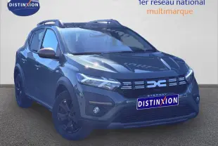 Vue 3/4 avant d'une Dacia Sandero Stepway 2025 en kaki lichen avec jantes noires et barres de toit.