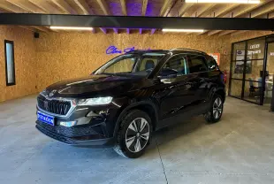 Vue 3/4 avant droite d’un Skoda Karoq noir 2024 avec calandre noire chromée et jantes alliage 17 pouces dans un garage.