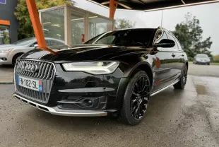 Audi A6 Avant Allroad noire vue en 3/4 avant droit, avec jantes noires et calandre chromée distinctive.