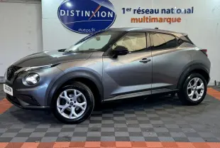 Profil droit d'un Nissan Juke gris clair 2021 dans un showroom avec logo Distinxion en arrière-plan.