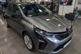 Renault Clio V Blue dCi 100 Evolution gris schiste vue 3/4 avant droit en intérieur showroom, calandre et phares modernes.