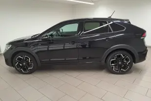 Profil côté gauche d'un Volkswagen Taigo noir intense nacré, avec jantes alliage R-Line et toit ouvrant visible.