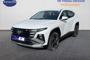 Vue 3/4 avant d'un Hyundai Tucson blanc Atlas 2026 avec calandre noire et jantes foncées contrastées.