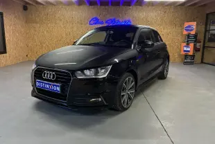 Audi A1 noir en 3/4 avant droit, avec jantes alliage et calandre S-Line visible dans un showroom intérieur.