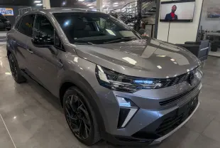 Renault Symbioz E-Tech gris Cassiopé en 3/4 avant droit, avec jantes noires et éclairage LED distinctif.