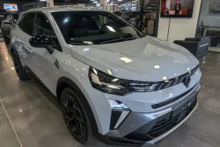 Vue 3/4 avant d'une Renault SYMBIOZ gris rafale avec jantes noires et détails noirs contrastants en intérieur showroom.