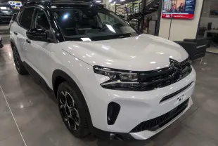 Citroën C5 Aircross hybride blanc Okénite avec toit noir Perla, vue 3/4 avant en showroom intérieur.