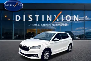 Vue 3/4 avant droite d'une Skoda Fabia blanche 2025 devant une vitrine avec logo Distinxion.