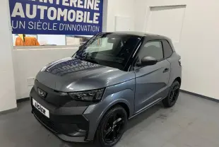 Vue 3/4 avant droite d'une Ligier JS50 Sport Elite E5+ gris métallisé avec jantes noires dans un showroom.