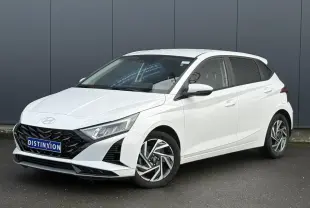 Vue 3/4 avant gauche d'une Hyundai i20 blanche Atlas avec jantes alliage diamantées et calandre noire distinctive.