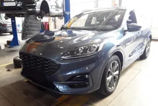 Ford Kuga 2024 bleu azur en 3/4 avant droit, avec calandre noire et jantes alliage visibles en atelier.