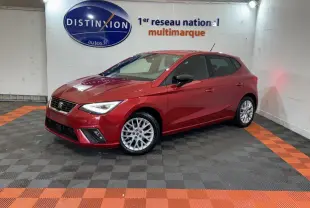 SEAT Ibiza 1.0 TSI 110 FR rouge vue 3/4 avant droit dans un showroom avec sol gris et bandes orange.