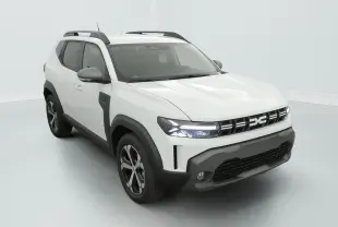 Vue 3/4 avant d'un Dacia Duster blanc avec éléments noirs, barres de toit noires et phares LED allumés.