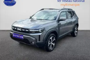 Dacia Duster gris schiste en 3/4 avant droit, avec barres de toit et jantes alliage distinctives.