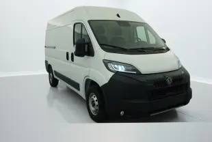Vue 3/4 avant droit du Peugeot Boxer Fourgon blanc 2025 avec calandre noire et phares allumés.