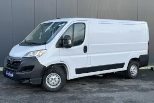 Vue 3/4 avant droit d’un Opel Movano Fourgon blanc 2024 avec pare-chocs noirs et rétroviseurs électriques rabattables.