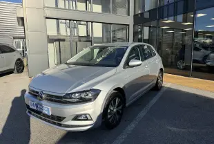 Volkswagen Polo gris métal vue 3/4 avant droit, avec jantes alliage et calandre noire brillante.