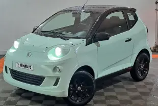 Vue 3/4 avant d'une Aixam Minauto E chic électrique 2025 vert clair avec jantes noires et phares allumés.