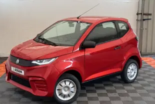 Vue 3/4 avant d'une Aixam Ambition E City Pack rouge électrique avec rétroviseur caméra côté gauche en intérieur showroom.