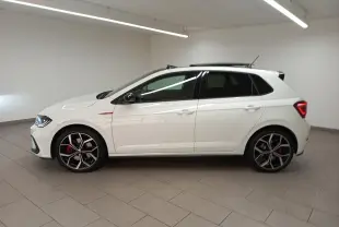 Vue de profil côté gauche d'une Volkswagen Polo GTI 2024 blanc pur avec toit noir et jantes sport noires et rouges.