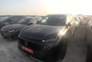 PEUGEOT 5008 gris foncé vue 3/4 avant droit, avec calandre noire et phares LED distinctifs au soleil couchant.