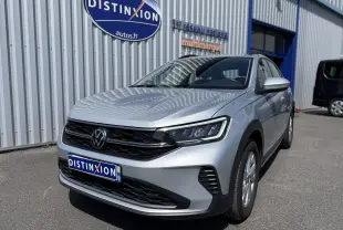 Volkswagen Taigo gris reflet d'argent métal en 3/4 avant droit, avec calandre noire et phares LED visibles.