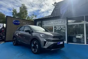 Renault Symbioz 1.8 E-Tech gris Cassiopée métallisé en 3/4 avant droit, avec jantes alu et calandre noire distinctive.