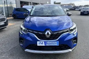 Vue de face d'un Renault Captur bleu métal 2022 avec calandre noire et logo Renault proéminent, sur parking extérieur.