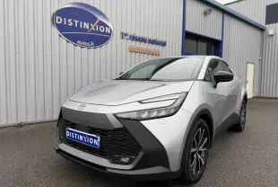 Toyota C-HR Hybride gris en 3/4 avant droit, avec calandre noire et phares LED fins visibles.