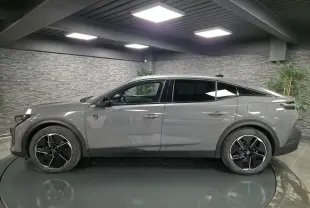 Profil droit de la Peugeot 408 gris métallisé avec jantes alliage noires et toit noir dans un showroom.
